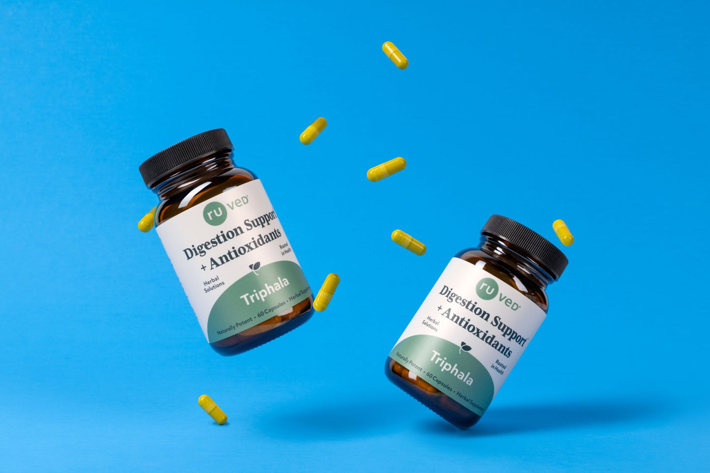 Two Triphala bottles and their capsules on a blue background.