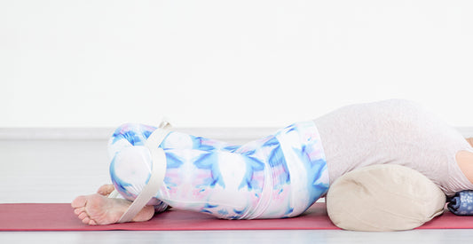 A person doing yoga and stretching over a pillow. 