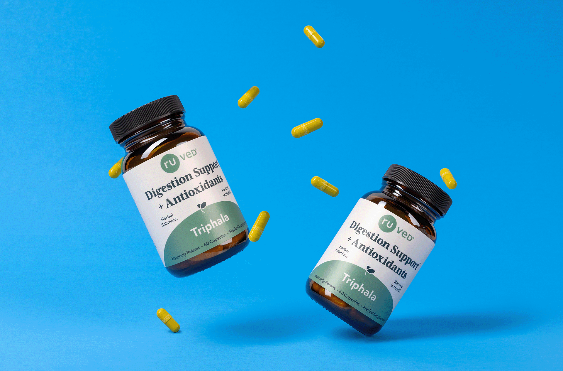 Two bottles of ruved Triphala and their capsules on a blue background. 