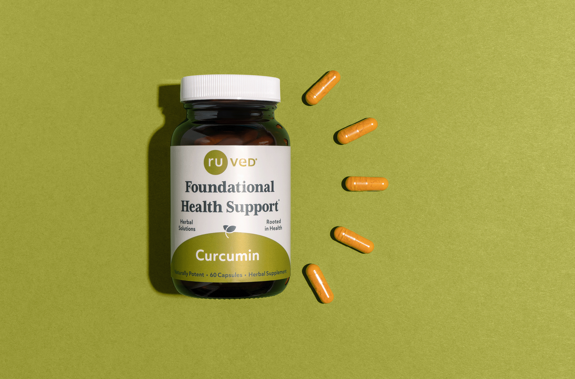 A Curcumin bottle laying next to capsules on a green background. 