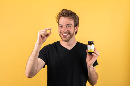 a man holding a bottle of Immune Daily smiling with a yellow background