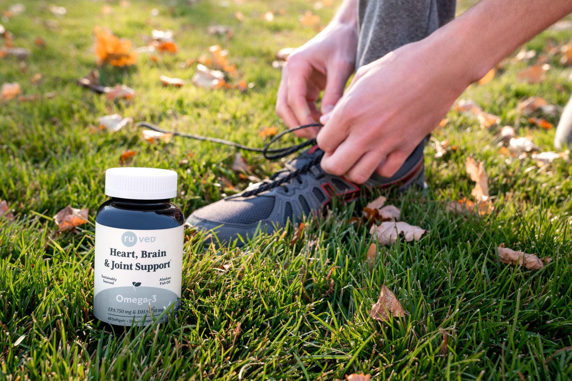 An Omega-3 bottle sitting next to a person tying their shoes.